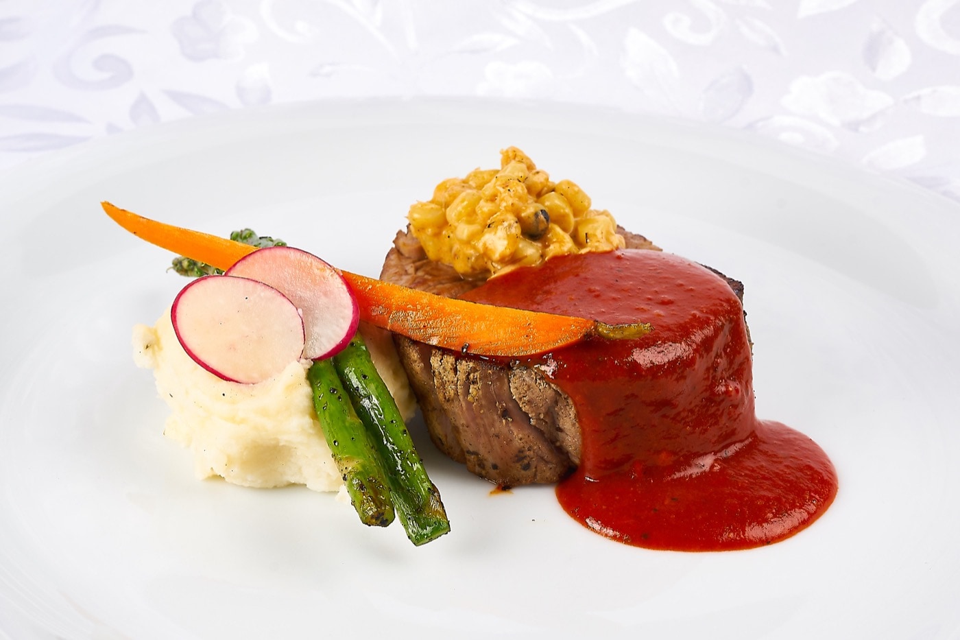 Filete de res con salsa de chile guajillo, acompañado de puré de maíz pozolero y esquites.